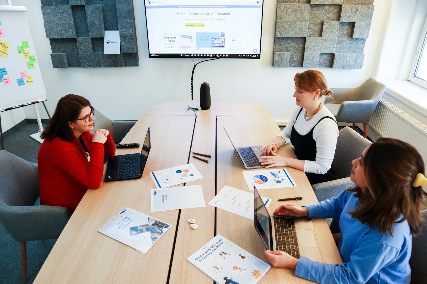 Trois femmes collaborent autour d'une table avec des ordinateurs portables dans un bureau.