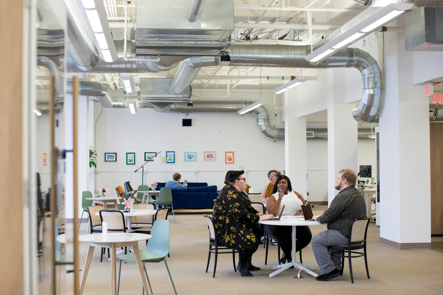 Équipe diversifiée collaborant autour d'une table avec des ordinateurs portables dans un bureau lumineux.